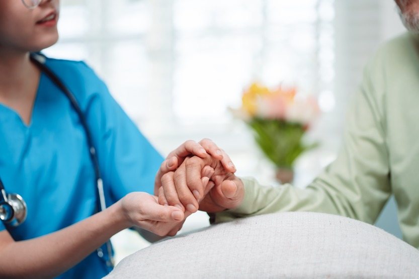 A nurse holding the hand of a dialysis patient