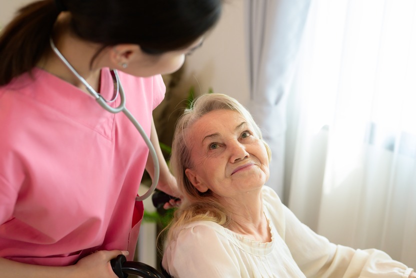 A photo of a caring nurse attending to a smiling senior in a wheelchair.